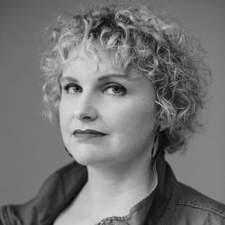 A monochrome headshot of Beth Howard with a subtle smile on a gray background.